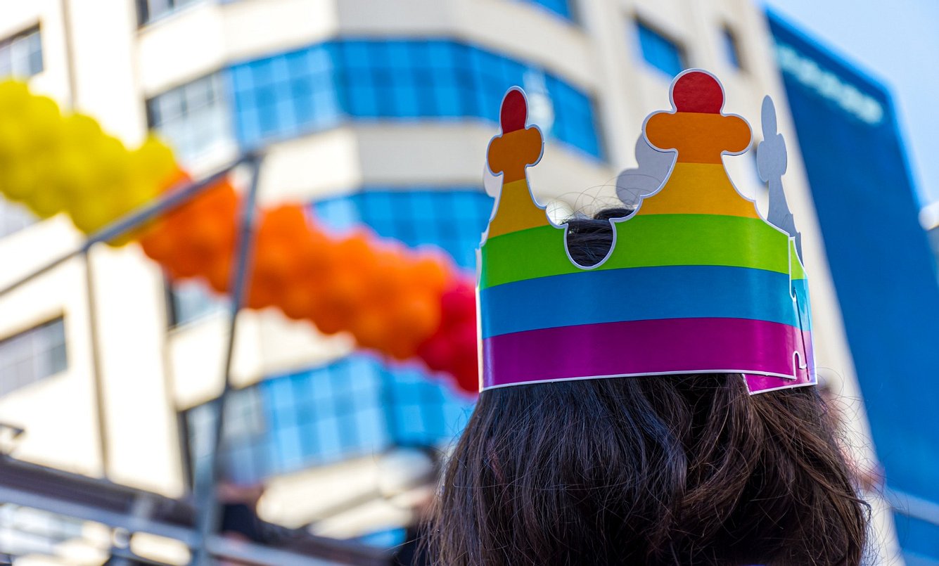pansexualitaet-was-ist-das Person mit einer bunten Krone auf dem Kopf schaut ein Hochhaus an