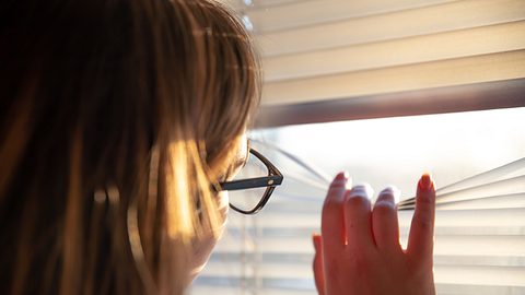 Eine Frau späht durch eine Jalousie - Foto: iStock/puhimec