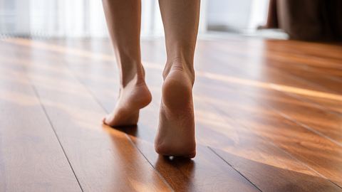 Nackte Füße einer Frau, sie geht auf Zehenspitzen über einen Parkettfußboden - Foto: istock/fizkes