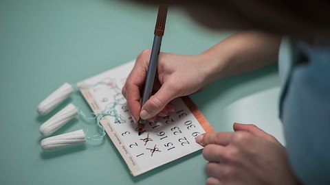 Frau schreibt in Periodenkalender - Foto: iStock/skynesher