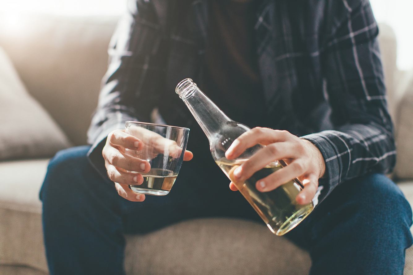 Ein Mann sitzt auf dem Sofa und trinkt Alkohol