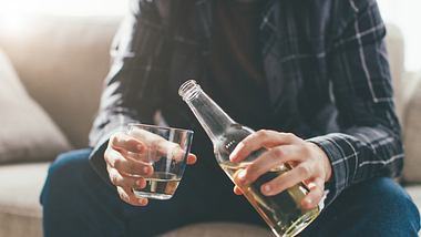 Ein Mann sitzt auf dem Sofa und trinkt Alkohol - Foto: iStock_eclipse_images