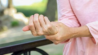 Eine Frau hält sich ihr Handgelenk - Foto: iStock/Motortion