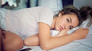 Eine Frau liegt mit Liebeskummer im Bett - Foto: iStock_praetorianphoto