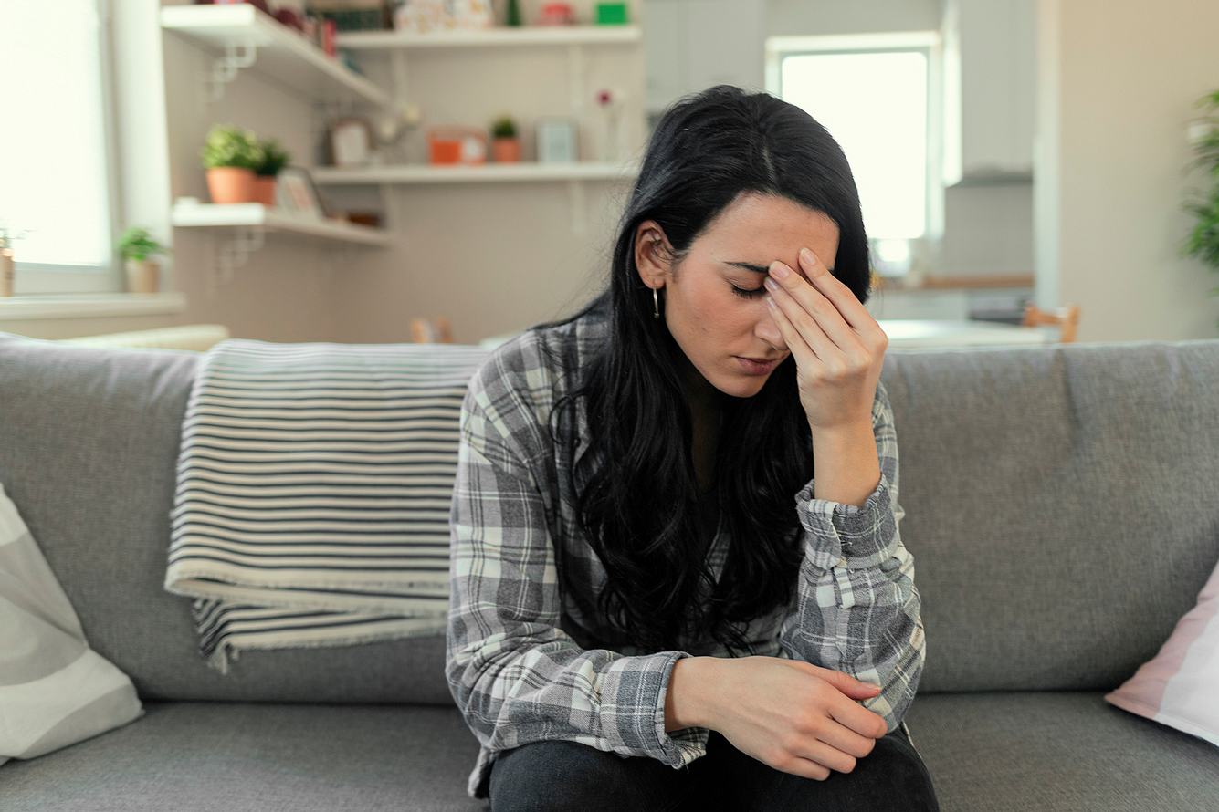 phobischer-schwankschwindel Eine Frau sitzt mit phobischen Schwankschwindel auf einem Sofa