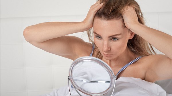 Frau geht sich durch ihre Haare - Foto: iStock/larszahnerphotography
