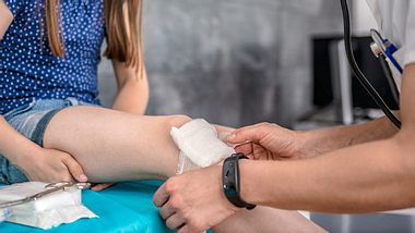 Arzt behandelt Platzwunde am Knie eines Mädchens - Foto: iStock/Kerkez