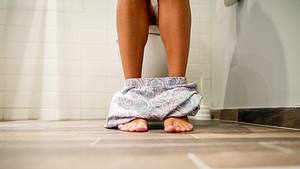 Person sitzt auf Toilette - Foto: iStock/dusanpetkovic