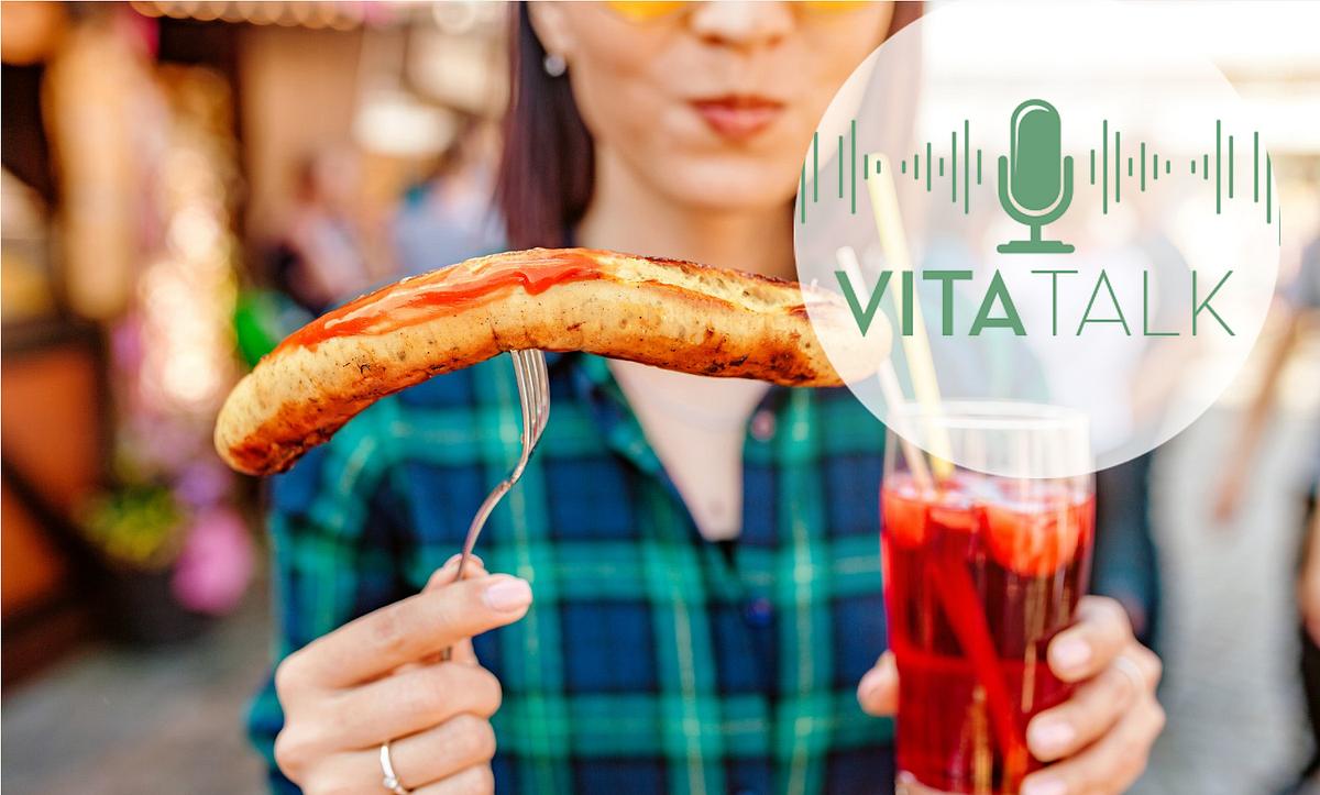 Frau hält Bratwurst und Glas