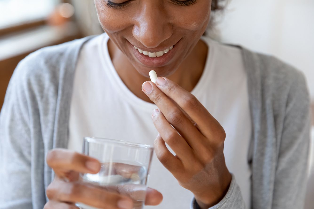 Frau hält eine Probiotika-Kapsel gegen Reizdarmsymptome in der Hand