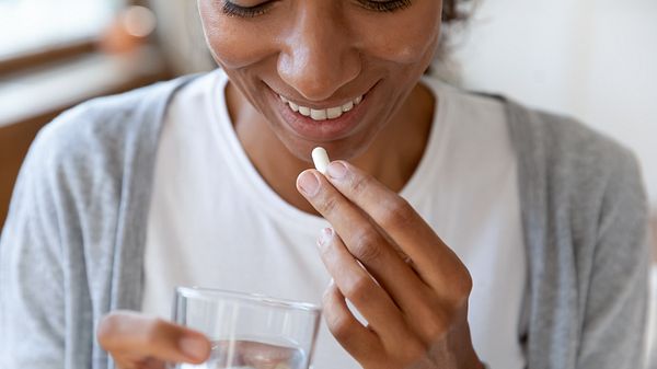 Frau hält eine Probiotika-Kapsel gegen Reizdarmsymptome in der Hand - Foto: iStock/fizkes