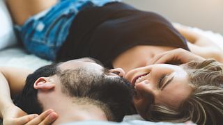 Mann und Frau liegen auf dem Bett und schauen sich an - Foto: iStock/tool51