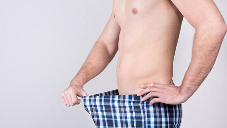 Mann mit Hodenentzündung guckt in seine Hose - Foto: iStock/diephosi