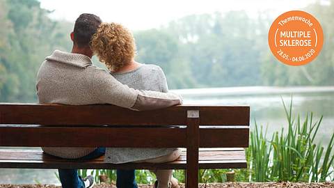 Paar mit MS sitzt auf einer Parkbank - Foto: iStock/m-imagephotography
