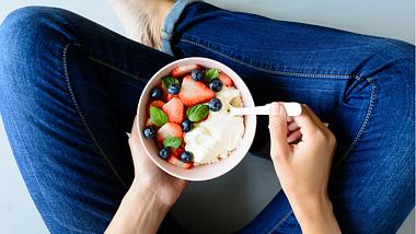 Eine Frau isst Quark mit Obst - Foto: iStock/TShum