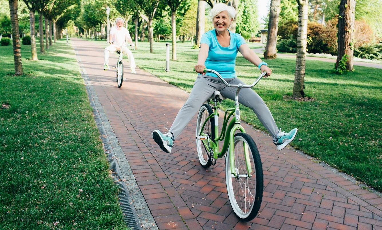 Ältere Dame sitzt auf dem Fahrrad und streckt ihre Beine aus