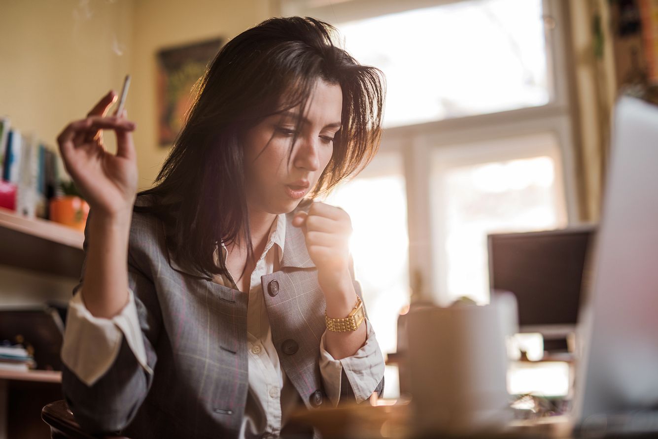 Eine junge Frau raucht bei Erkältung und hustet