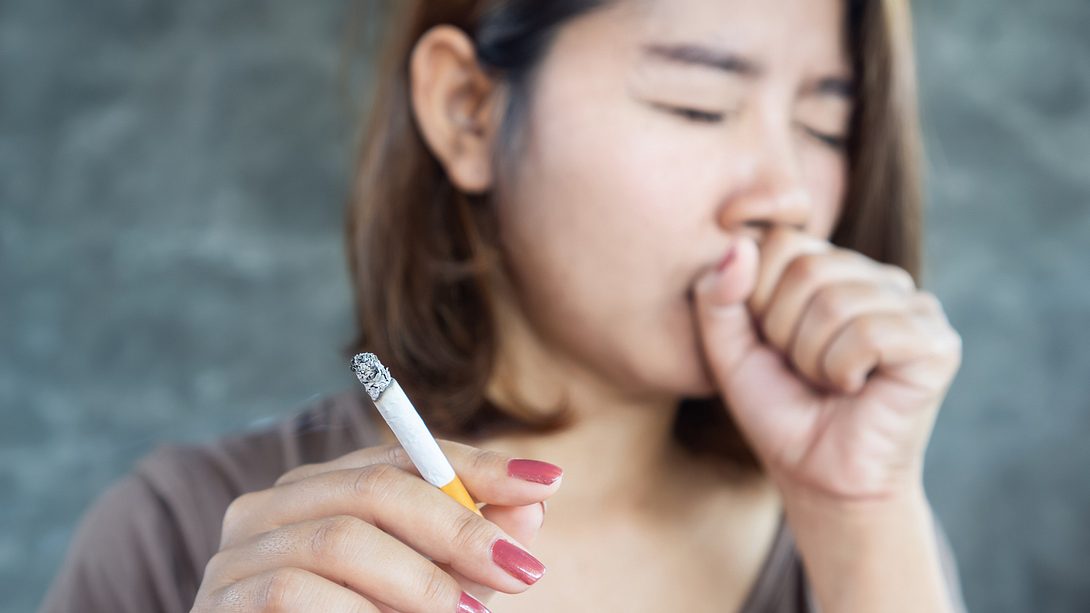 Frau hat Raucherhusten und hält Zigarette in der Hand - Foto: iStock/Doucefleur