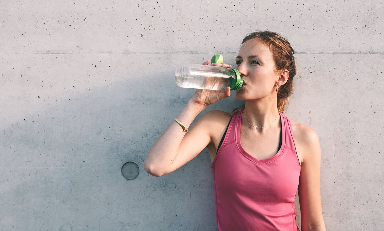 Eine Frau trinkt in einer Trainingspause Wasser