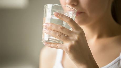 Eine Frau trinkt ein Glas Wasser - Foto: iStock/fizkes