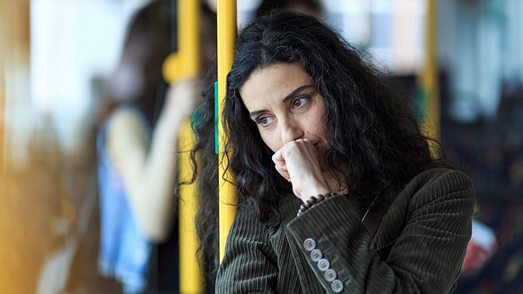 Frau steht im Bus und leidet an Reiseübelkeit - Foto: iStock/valentinrussanov