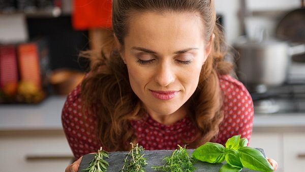 Eine Frau riecht an Kräutern - Foto: Fotolia