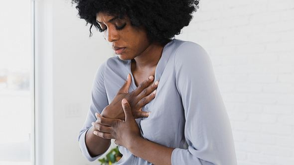Eine Frau greift sich an die Brust - Foto: iStock/SDI Productions