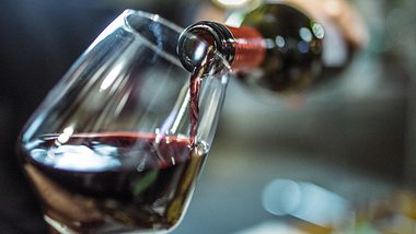 Jemand schenkt Rotwein in ein Glas ein - Foto: iStock_Instants