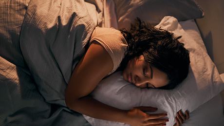 Eine Frau liegt schlafend in ihrem Bett - Foto: iStock_Adene Sanchez