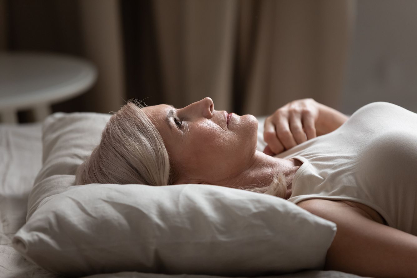 Eine Frau liegt mit geöffneten Augen im Bett