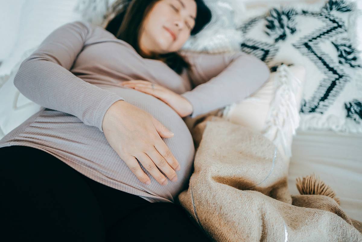 Eine schwangere Frau schläft auf der linken Seite