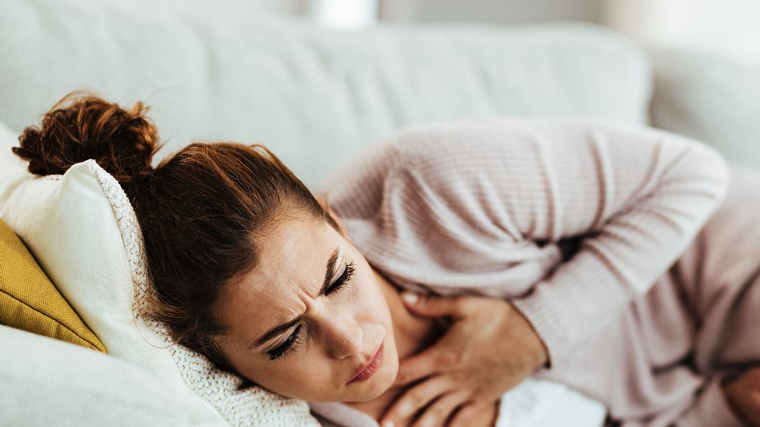 Eine Frau liegt mit Atemnot auf dem Sofa - Foto: iStock_Drazen Zigic