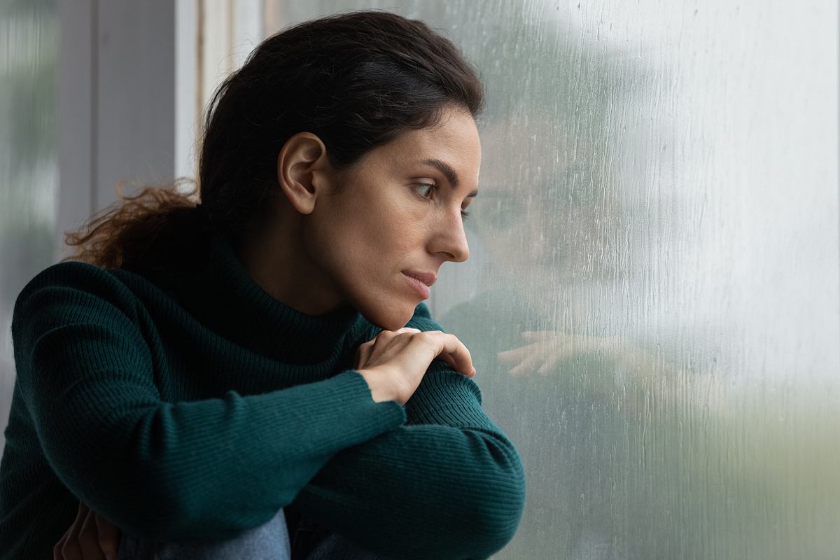 Frau guckt traurig aus dem Fenster