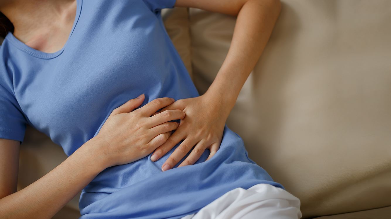 Eine Frau liegt mit Schmerzen im linken Oberbauch im Bett 