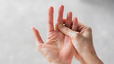Linke Handinnenfläche vor weißem Hintergrund abgebildet. Die rechte Hand hält den linken Mittelfinger fest. - Foto: iStock/Chainarong Prasertthai