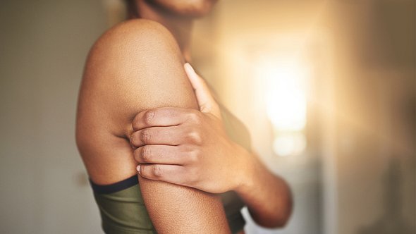 Frau hält sich den schmerzenden Arm - Foto: istock/peopleimages