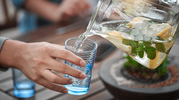 Person gießt sich Wasser in ein Glas - Foto: istock/peopleimages