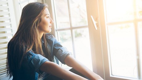 Eine Frau sitzt am Fenster - Foto: portishead1/iStock