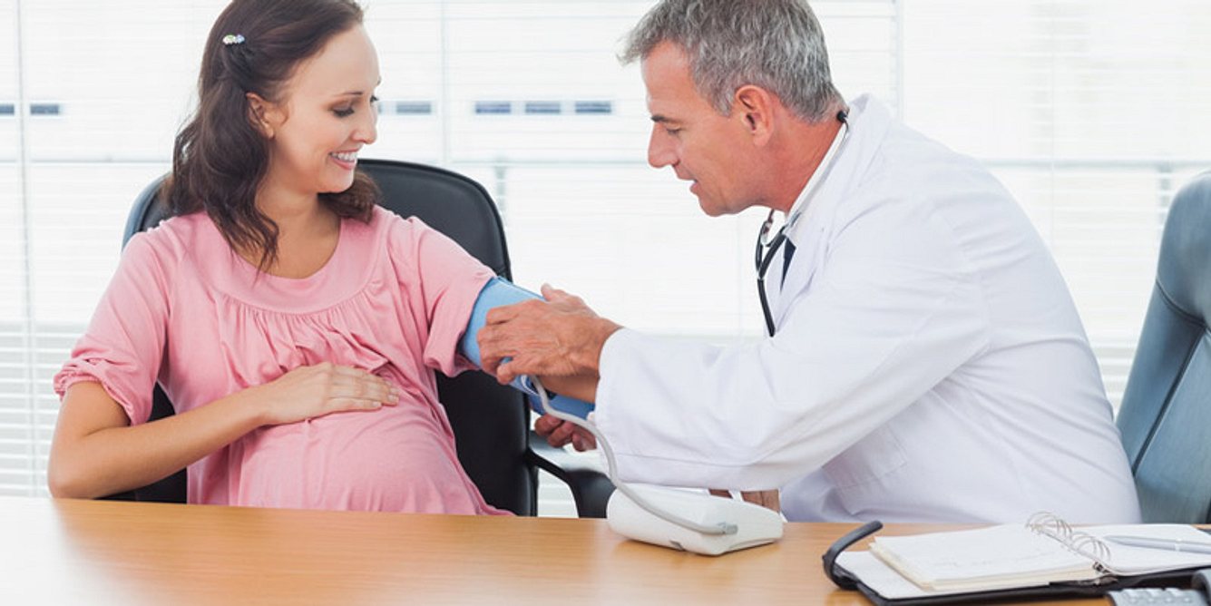 Ein Arzt misst den Blutdruck einer Schwangeren