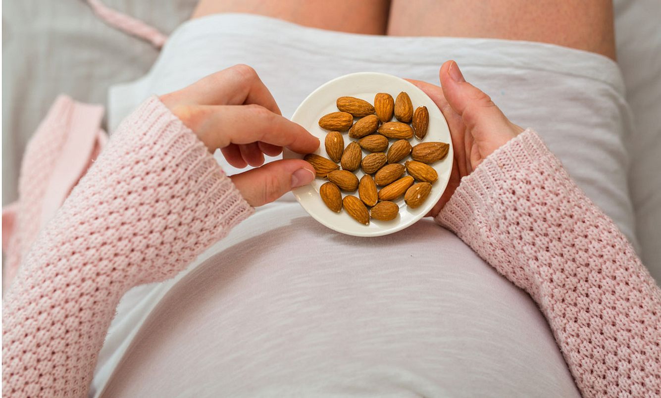 Schwangere isst Mandeln gegen Magnesiummangel in der SSW 22