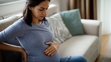Schwangere Frau hält sich den Bauch und hat Schwangerschaftsbeschwerden - Foto: iStock/damircudic