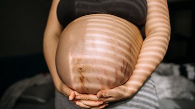 Eine schwangere Frau mit rundem Bauch, auf dem viele Dehnungsstreifen sind - Foto: istock_Pekic