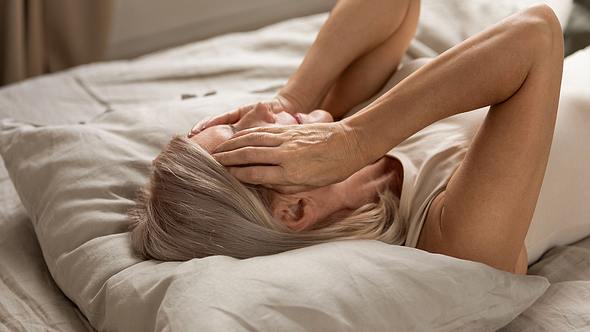 Frau mit Kopfschmerzen im Bett - Foto: iStock / fizkes