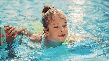 Ein Mädchen schwimmt im Schwimmbecken - Foto: iStock/eljkosantrac