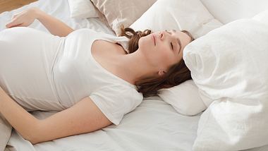 Schwangere Frau liegt im Bett - Foto: iStock/Demkat