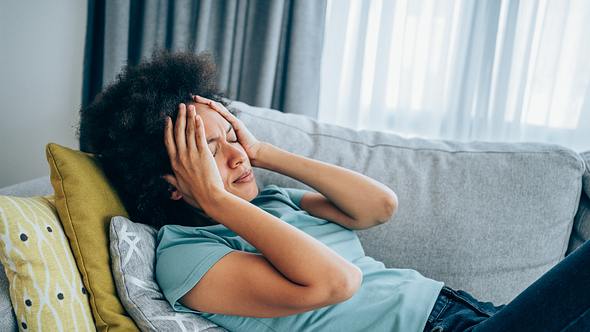 Eine Frau liegt mit Schwindel auf dem Sofa - Foto: iStock_VioletaStoimenova
