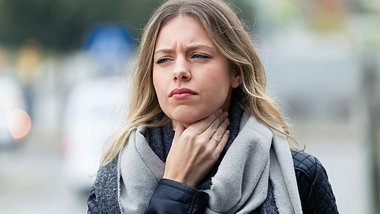 Frau hält sich den schmerzenden Hals - Foto: iStock/nensuria