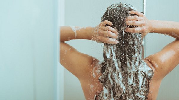Eine Frau steht unter der Dusche und wäscht sich die Haare - Foto: CentralITAlliance/iStock