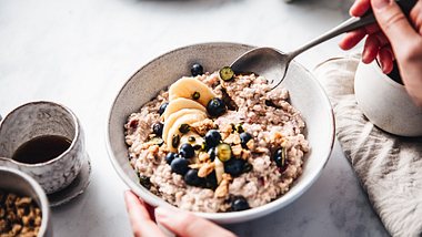 Eine Nahaufnahme einer Schale mit Porridge, Blaubeeren und Bananen - Foto: istock_alvarez