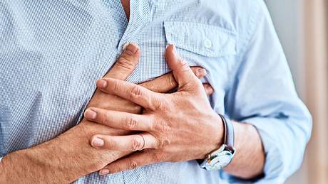 Ein Mann leidet unter Sodbrennen und hält sich die Hände vor der Brust - Foto: iStock/PeopleImages